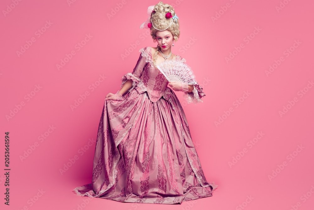 Fototapeta premium Full length photo of happy attractive lady dressed baroque costume waving hand fan copy space isolated pink color background