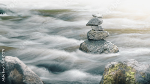 Photography Stack of balanced Zen stones standing in a fast flowing river with long exposure