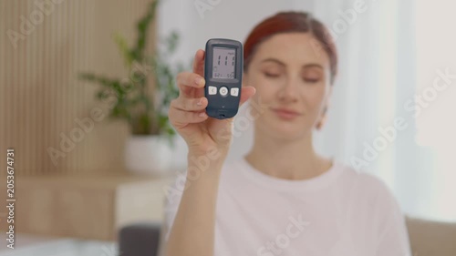 A woman shows her glucometer reading of 111 mg dL in a home environment. She discusses what this means for blood sugar levels and health management.