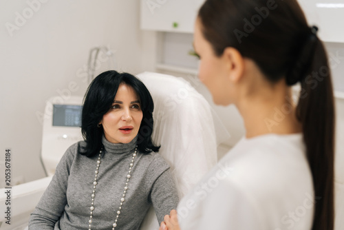 Foto Rear view of female beautician giving professional advice to middle-aged woman client in cosmetology office, explaining cosmetic procedures for skin enhancement and antiaging care
