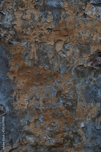 Close-up of an old weathered concrete wall with peeling brown paint and dark gray decay, showcasing a rough grunge texture ideal for background design.