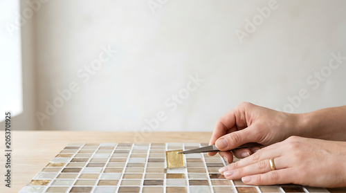 Hands placing mosaic tile isolated on a clean white background