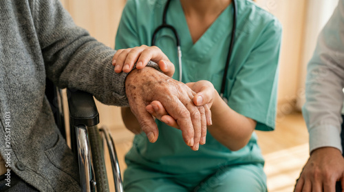 Compassionate caregiver holding hands with an elderly patient offering support and comfort.