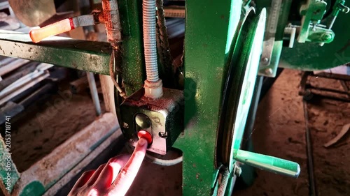Carpenter pressing red button on woodworking machine to start sawing timber log in a sawmill