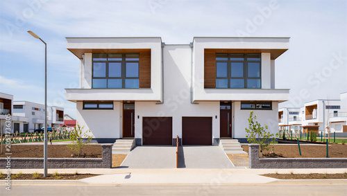 Foto Modern white duplex townhouses with brown garages and clean architectural design