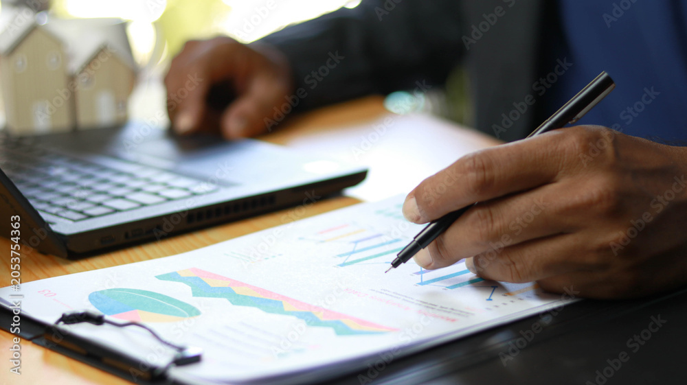 Fototapeta premium Real estate consultant analyzing property investment performance and housing market reports on a laptop. Mortgage planning, financial analysis, real estate management, homeownership and business 