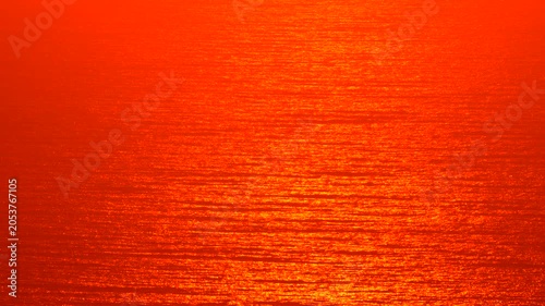 Sunset ocean water texture, deep red orange reflection background, abstract summer sea surface motion, vibrant color grading.