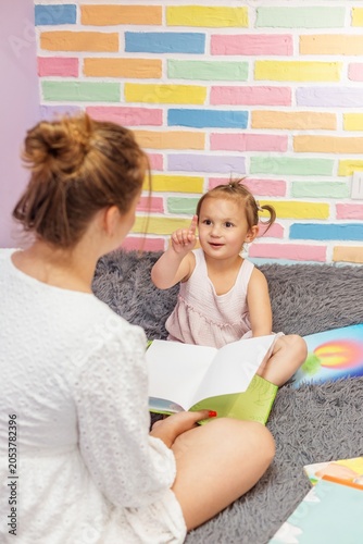 Mother and child reading book together at home
