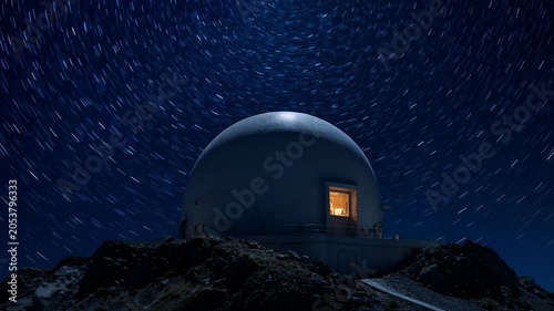 Observatory structure illuminated against a night sky with starry backdrop