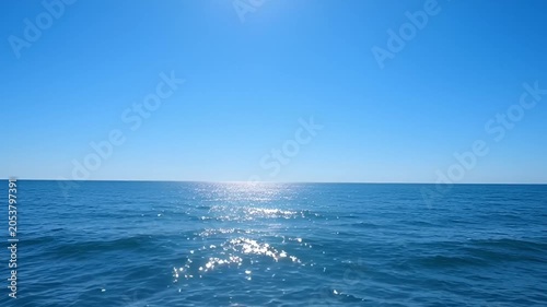 Ocean expanse under a clear blue sky horizon and bright sunlight