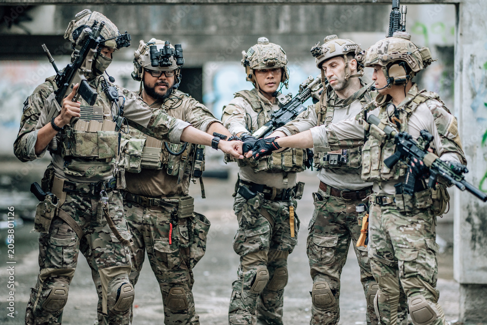 Fototapeta premium Tactical team celebrates mission success raising helmets and fists together in abandoned building