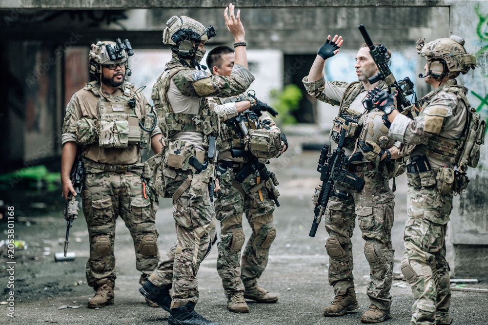 Fototapeta premium Tactical team celebrates mission success raising helmets and fists together in abandoned building