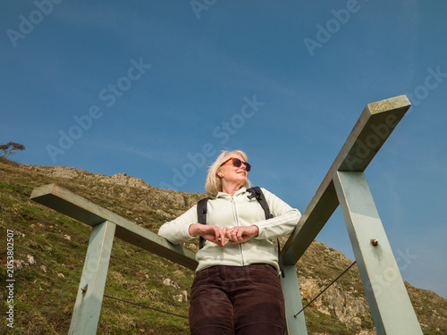 Tableau sur toile Senior female hiker wearing sunglasses looking out from view point in mountains