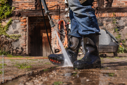 Bauer reinigt seine Stiefel mit Wasser