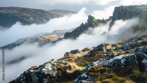 Moody mountain landscape with dramatic fog rolling through valleys and rocky peaks