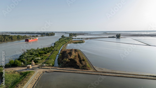 Fotografie Cargo ship navigating Guadalquivir river in rice paddies region