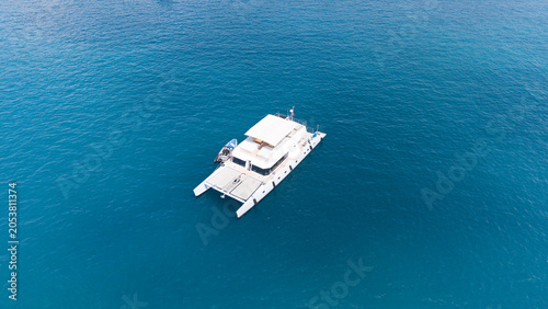 Foto Catamaran in Azure Waters: An elegant catamaran sails serenely on the deep blue, tranquil ocean, offering a luxurious escape and adventure on the sea