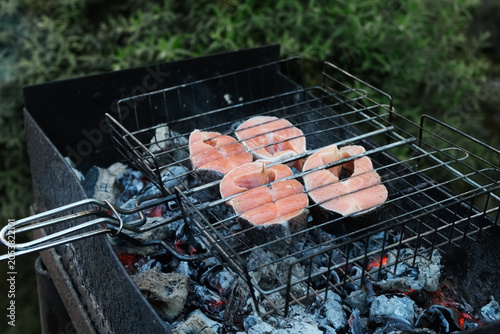 Grilling steaks of salmon fish outdoors. Summer barbecue, cookout, picnic