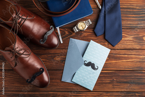  Father's Day concept with shoes, tie, watch, and greeting card on wood surface