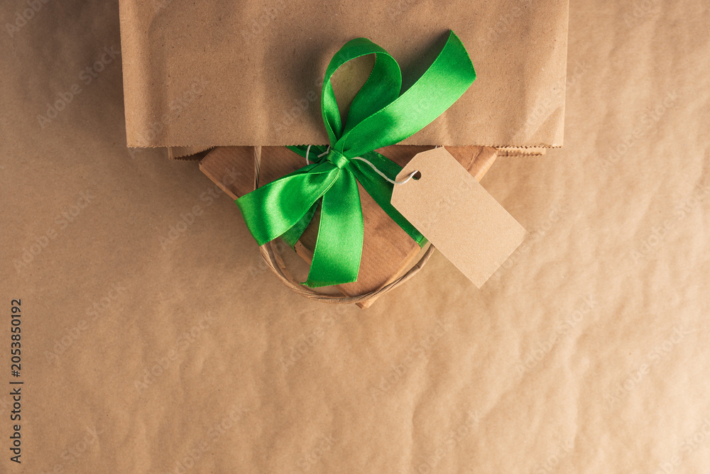 Fototapeta premium Craft gift box with green ribbon and blank tag in a bag