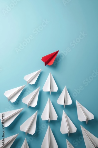 One red paper plane leading a group of white paper planes in a conceptual business leadership concept
