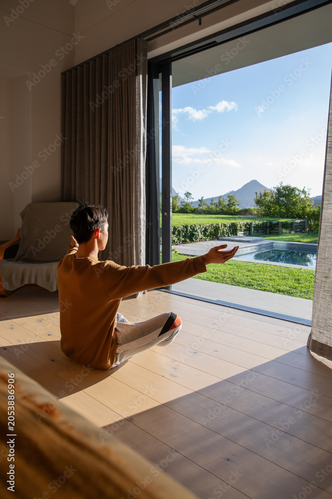Naklejka premium Sunlight is streaming through open sliding glass door onto wooden plank floor, casting long shadows