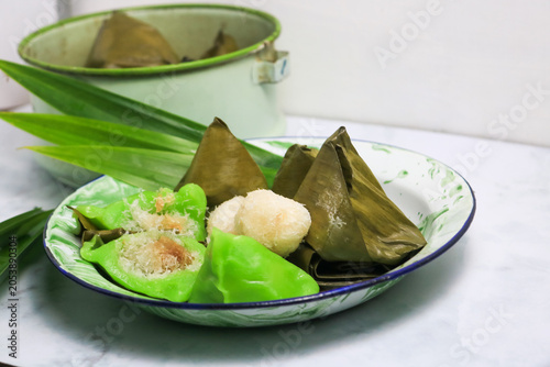 Traditional Indonesian Mendut cake with pandan leaves. Javanese sweet snack is made from glutinous rice flour, coconut and palm sugar, then wrapped in banana leaves and steamed. white backround.