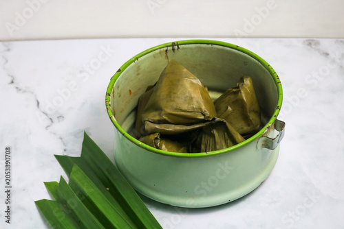 Traditional Indonesian Mendut cake with pandan leaves. Javanese sweet snack is made from glutinous rice flour, coconut and palm sugar, then wrapped in banana leaves and steamed. white backround.