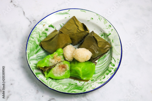 Traditional Indonesian Mendut cake with pandan leaves. Javanese sweet snack is made from glutinous rice flour, coconut and palm sugar, then wrapped in banana leaves and steamed. white backround.