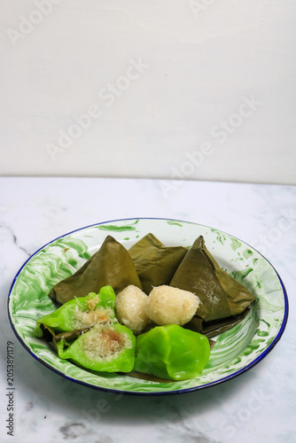 Traditional Indonesian Mendut cake with pandan leaves. Javanese sweet snack is made from glutinous rice flour, coconut and palm sugar, then wrapped in banana leaves and steamed. white backround.