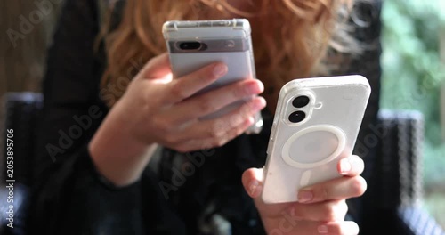 Holding two smartphones in one hand and transferring information from one to the other.