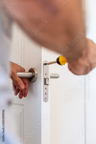 Obraz na plátně Handyman repairing door lock mechanism with screwdriver