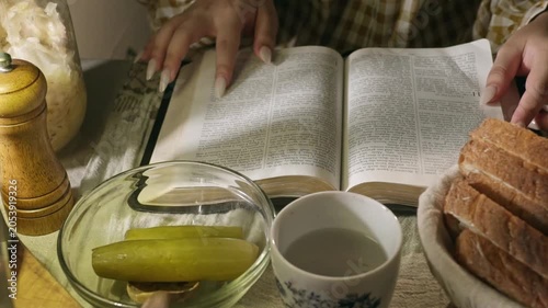 young conservative asian Woman Reading the Bible at table with bread food and drink indoors