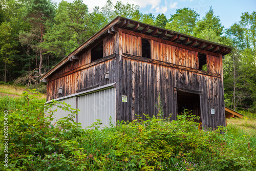 Old wooden barn stands in green landscape under blue sky