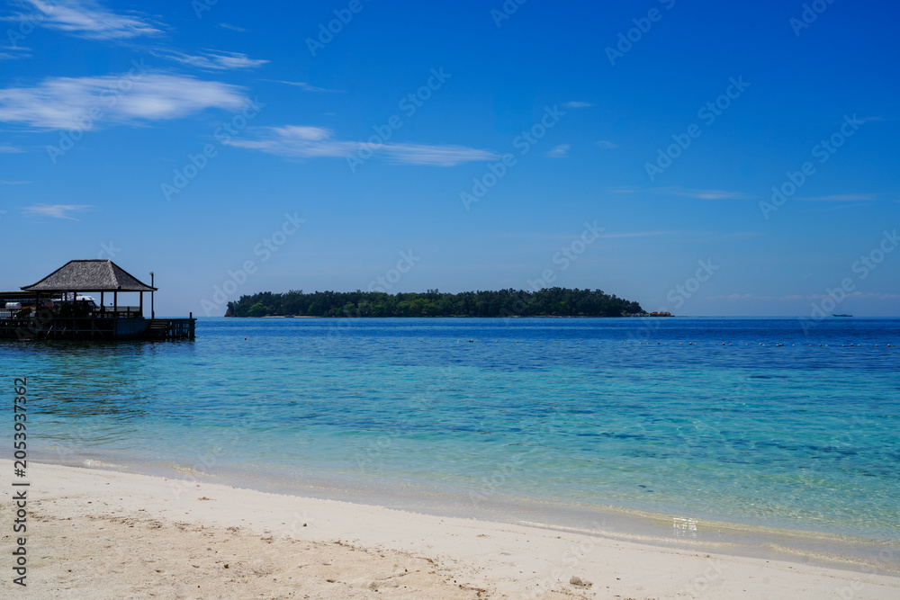 Fototapeta premium Beautiful tropical beach with a wooden jetty and crystal clear turquoise sea at Sepa Island resort, Thousand Islands, Jakarta, Indonesia.