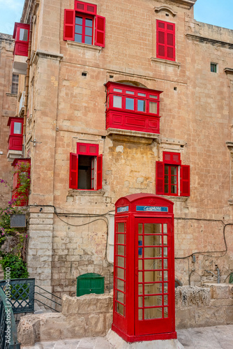 Street scene with British red telephone box against house with maltese red balconies in Valletta. Malta