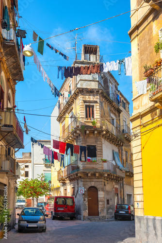 Clothes are dried on ropes between buildings in street at historical district of Catania. Sicily, Italy