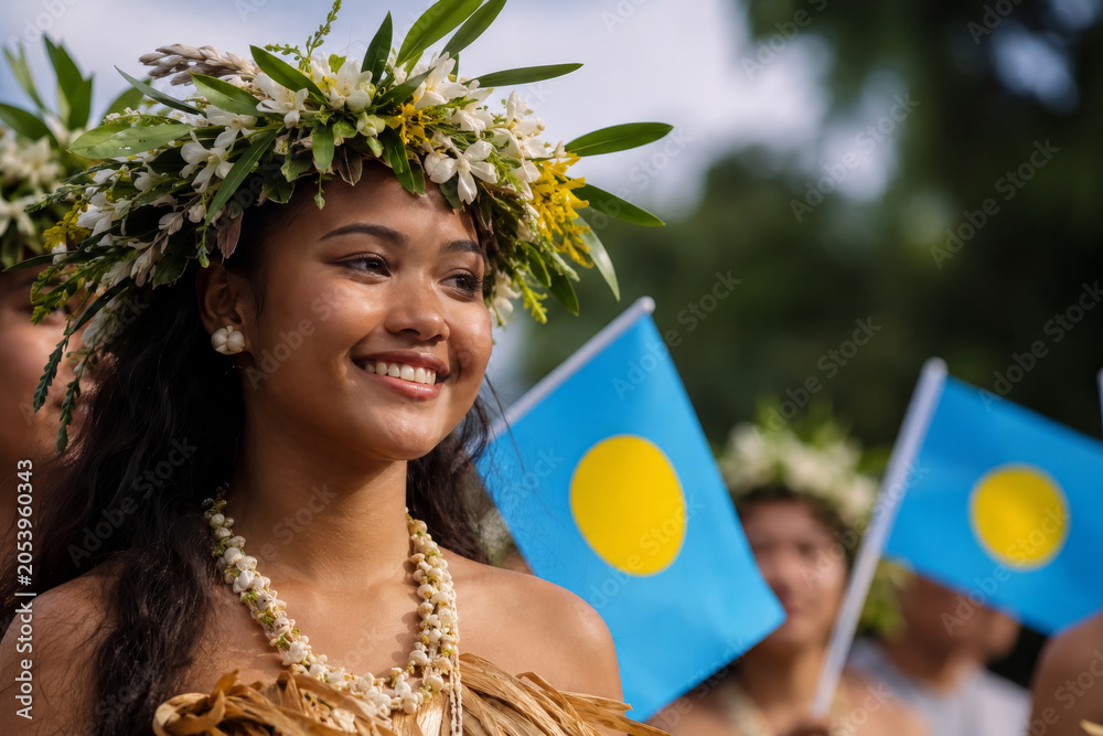 Obraz premium Portrait of woman wearing a floral headpiece, celebrating Constitution Day in Palau with flags.