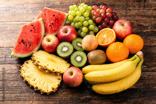 Assorted Fresh Fruits Including Watermelon, Pineapple, Apples, Bananas, Kiwi, Grapes and Oranges on Wooden Surface