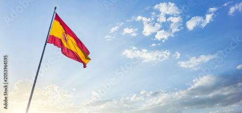 Flag of Spain waving at the top of a post with a bottom of sunny blue sky