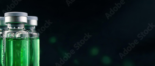 Medical glass vials with bright green solution and rubber stoppers lined up against a dark abstract background.