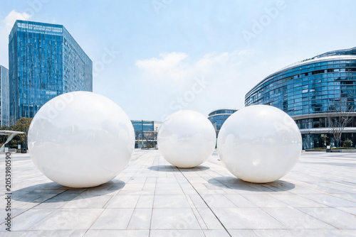 Modern urban plaza with large white spherical sculptures and contemporary glass buildings