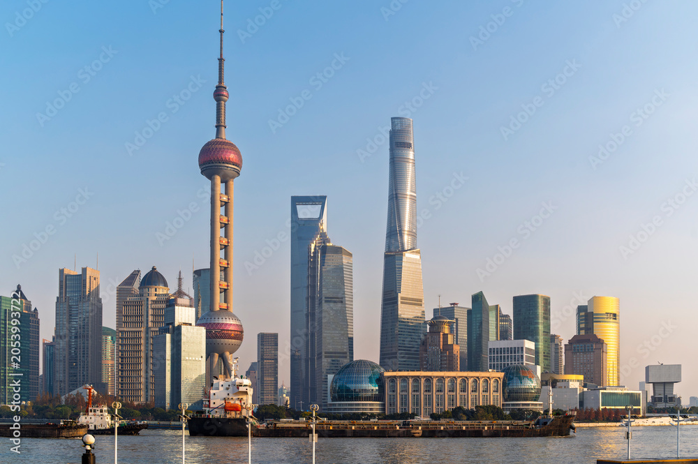 Fototapeta premium Sun rise of Shanghai city modern skyscraper cityscape in blue sky autumn season behind pollution haze, view from the bund in Shanghai, China.