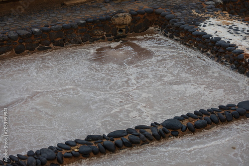 Fotografia Crystallization process of sea salt inside traditional stone pond at Salinas del