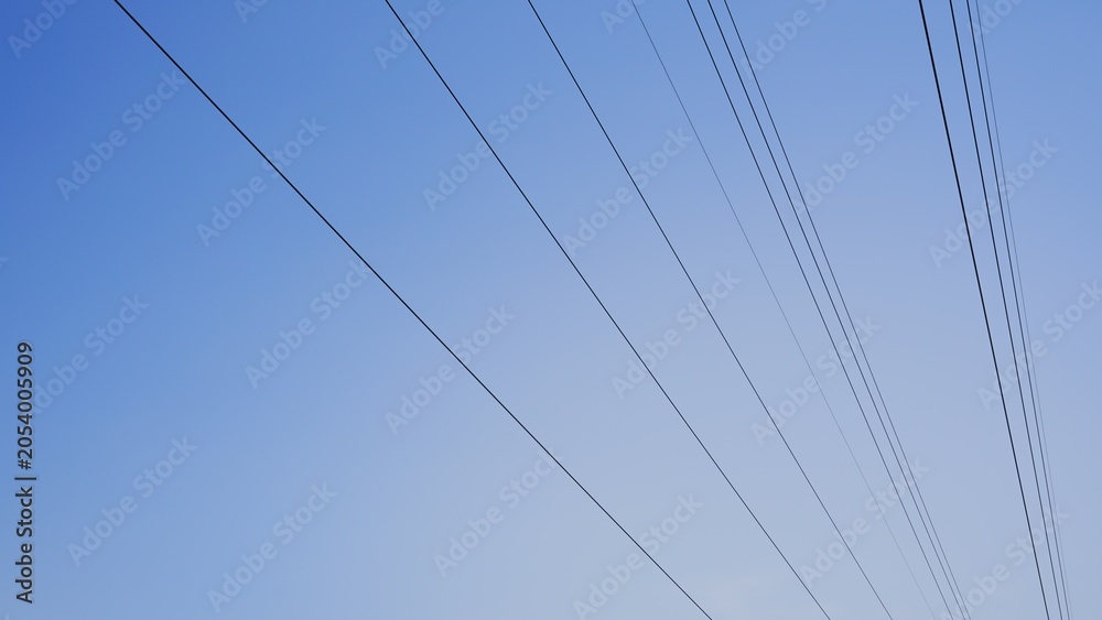 Fototapeta premium Parallel high voltage power lines against clear blue sky background