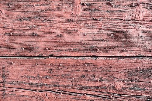 Weathered pink painted wooden planks with rusty nails.