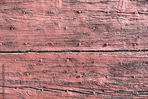 Weathered pink painted wooden planks with rusty nails.