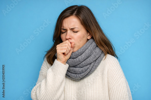 A woman covering her nose with her hand as she sneezes.