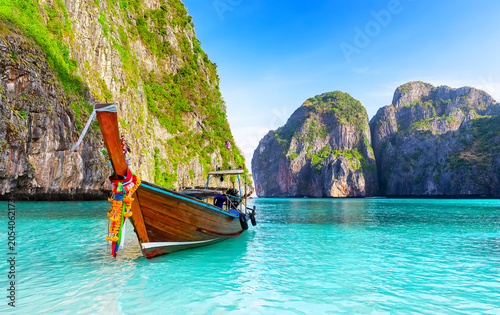 Traditional Thai longtail boat floating in the turquoise waters of Maya Bay on Phi Phi Islands, Thailand. One of the most iconic tropical travel destinations in Southeast Asia.