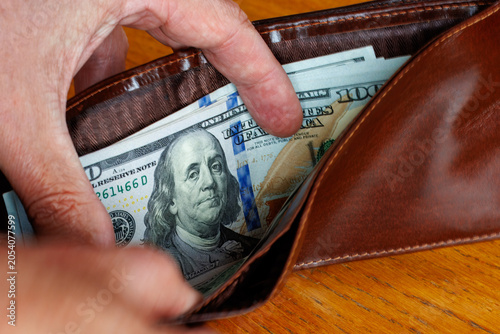 Quadro em tela Hand taking a 100 dollar bill banknote from wallet, cost of living, wages, or inflation concept